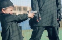 لقطة من شريط فيديو أصدرته داعش، يظهر أحد المتشددين وهو يعطي مسدسا لطفل. وبعد ذلك بلحظات، يظهر الطفل نفسه في الفيديو وهو يطلق النار على أحد ’المرتدين‘ وأرداه قتيلاً.