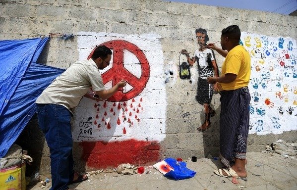 Un artiste yéménite peint un graffiti sur un mur de Sanaa représentant le symbole de paix saignant, en référence à la guerre en cours qui déchire le pays depuis quatre ans et à l'échec des négociations pour une résolution pacifique. [Mohammed Huwais/AFP]