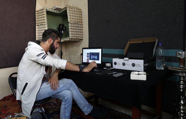Al-Muarri travaille sur son ordinateur dans sa chambre à Maaret al-Numan. En plus du rap à l'ancienne, il dit aimer les compositeurs classiques comme Beethoven et Vivaldi. [Omar Haj Kadour/AFP]