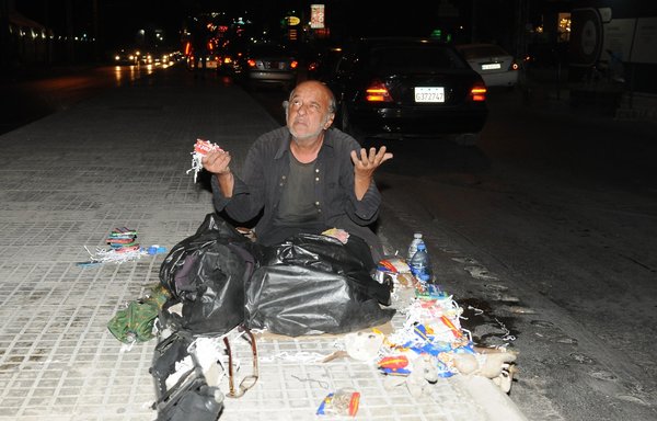 This man has been sleeping on a sidewalk in Lebanon's Dora district for months, after becoming unable to pay his rent, and now he scrounges for leftover food in the garbage. [Ziad Hatem]