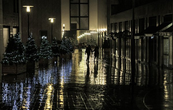 رجل وامرأة يسيران تحت الأمطار على طول الشارع الغارق بالمياه، ويمرون أمام متاجر مغلقة في منطقة التسوق الراقية 'أسواق بيروت' بالعاصمة اللبنانية يوم 14 كانون الأول/ديسمبر. [جوزيف عيد/وكالة الصحافة الفرنسية]