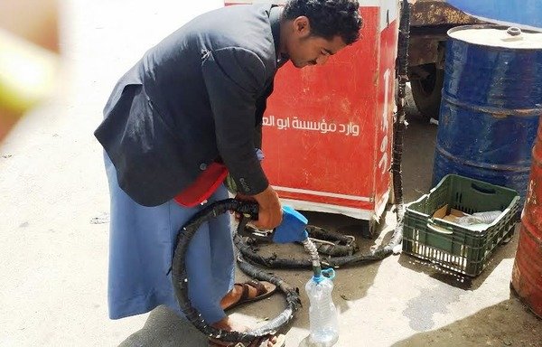 A Yemeni man fills up a bottle with gasoline in Sanaa. Due to the ongoing war, citizens are turning to the black market to sell and buy oil derivatives. [Faisal Darem/Al-Shorfa]