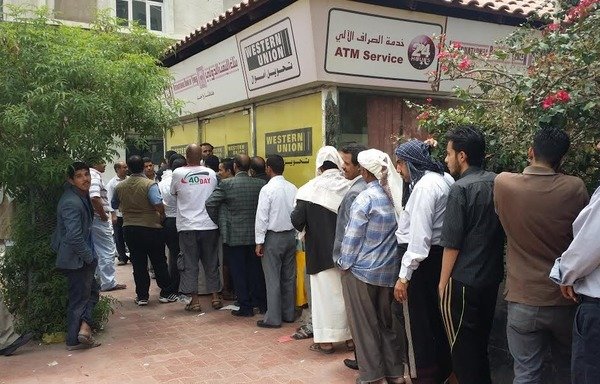 يمنيون ينتظرون لسحب رواتبهم من صرّاف آلي. [فيصل دارم/المشارق]