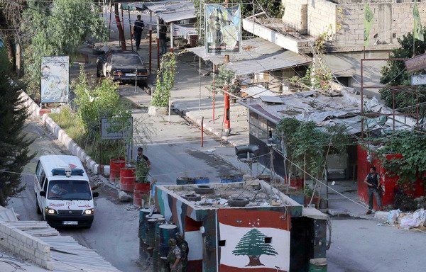 جنود من الجيش اللبناني يراقبون سيارة أسعاف وهي تغادر مخيم عين الحلوة للاجئين الفلسطينيين بالقرب من مدينة صيدا جنوب لبنان، في شهر آب/أغسطس من العام 2015. [محمود زيات/وكالة الصحافة الفرنسية]