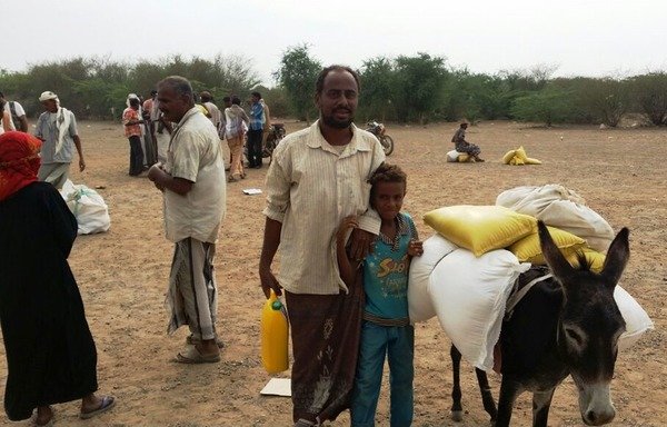 A Yemeni father and son receive food aid in the coastal province of al-Hodeida. [Photo courtesy of Angela for Development and Humanitarian Response]
