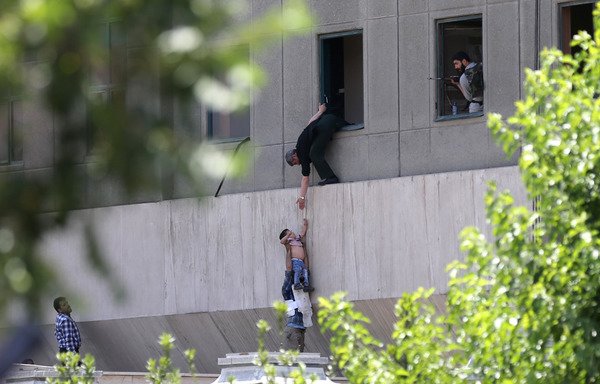 Iranian policemen evacuate a child from the parliament building in Tehran on June 7th, during an 'Islamic State of Iraq and Syria' attack. [Omid Vahabzadeh/FARS NEWS/AFP]