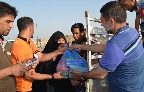 Ramzi al-Azzawi distributes aid donated by different people to displaced families in Baghdad's al-Jamia neighbourhood. [Photo courtesy of Ramzi al-Azzawi]