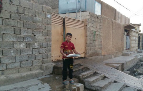 A young Iraqi boy carries a tray of food to share with his neighbours after they break their fast, a Ramadan tradition that Iraqis have kept.