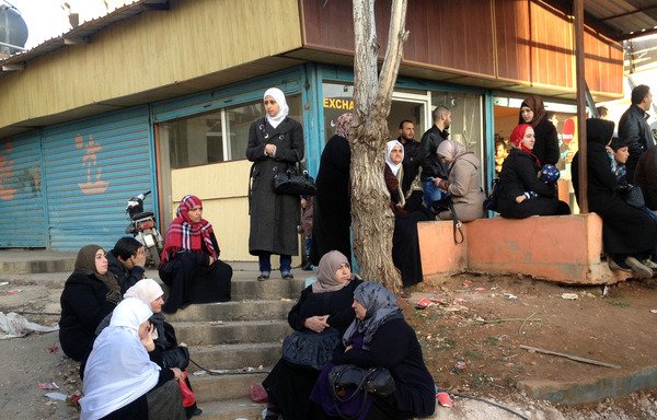 سوریه های درانتظار رسیدن یک کاروان حامل بستگان خودشان درنزدیکی گذرگاه مرزی المصنع درروز 28 دسامبر دیده می شوند. [حسن جراح/ خبرگزاری فرانسه]