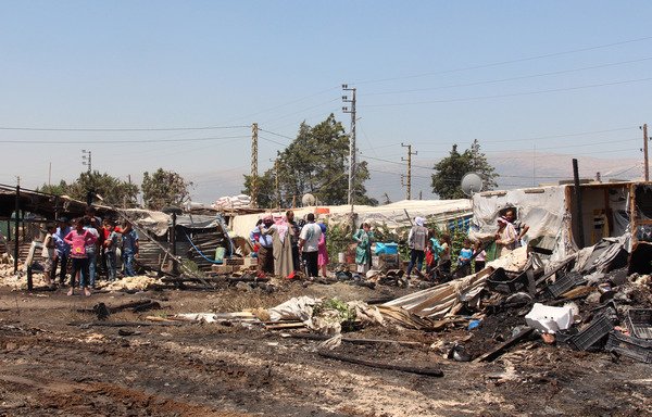 Syrian refugees look at the damage after a fire engulfed part of the Tel al-Sarhoun refugee camp near the Bekaa Valley town of Bar Elias on July 4th. [Hassan Jarrah/AFP]