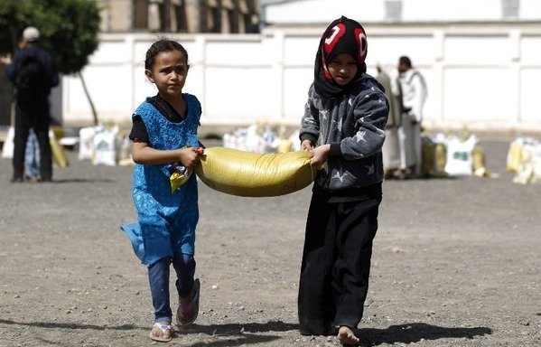 Yemeni children carry food aid distributed by a local charity during the Muslim holy fasting month of Ramadan, in the capital Sanaa, on June 7th. A new campaign in Hadramaut province aims at promoting a culture of peace and tolerance among Yemeni school-age children. [Mohammed Huwais/AFP]