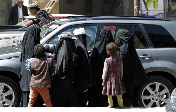 Yemeni women and children beg drivers for money on a street in Sanaa on October 27th, 2016. Economists warn that a recent drop in the currency exchange rate will contribute to rising poverty. [Mohammed Huwais/AFP]