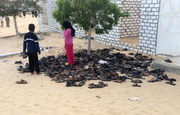 Des enfants égyptiens près d'une pile de chaussures ayant appartenu aux victimes de l'attaque du 24 novembre contre la mosquée d'al-Rawda, près d'al-Arish, la capitale provinciale du Sinaï Nord. [STR/AFP]