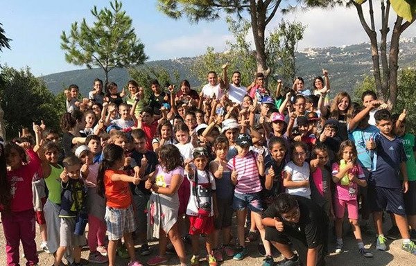 بچه های کلدانی عراقی و آموزگاران آنها برای گرفتن یک عکس گروهی در پایان یک فعالیت در مرکز بانوی رستگاری و مهر درمرکز اجتماعی مسیحی در سد البوشریه که برای آنان برگزار شده بود ژست می گیرند. این مرکز به تازگی یک مدرسه و مرکز آموزش حرفه ای برای بچه های کلدانی پناهنده درلبنان گشود. [عکس با کسب اجازه از مرکز بانوی رستگاری و مهر در مرکز اجتماعی مسیحی]