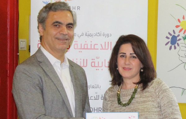 Academic University College for Non-violence and Human Rights president Issam Mansour presents a course participant with a certificate. [Photo courtesy of AUNOHR]