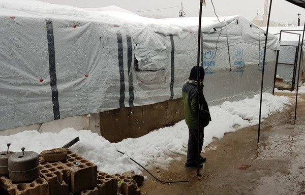 رجل يقف في البرد والثلج في مخيم للاجئين في عرسال. [حقوق الصورة لخالد رعد]