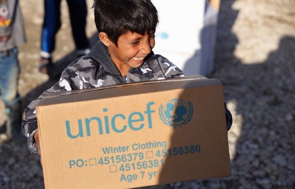 طفل لاجئ سوري في لبنان يتلقى من اليونيسف علبة تحتوي على ملابس شتوية. [حقوق الصورة لليونيسف]