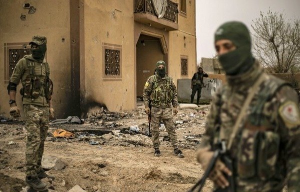 اعضای نیروهای دموکراتیک سوریه در روز 24 مارس یک روز پس از اعلام شکست داعش بوسیله این نیروها در روستای الباغوز راه می روند.[دلیل سلیمان/خبرگزاری فرانسه]