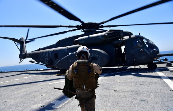 Un pilote à côté d'un MH-53E Sea Dragon sur le pont du porte-hélicoptères Lewis B. Puller lors d'un exercice conjoint de déminage entre les marines des États-Unis, du Royaume-Uni et de la France dans le golfe Persique le 15 avril 2019. [Giuseppe Cacace/AFP]