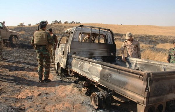 Iraqi army and tribal fighters inspect a truck bombed by Iraqi aircraft in Wadi Houran in western Anbar on August 20th. [Photo courtesy of the Iraqi Ministry of Defence]
