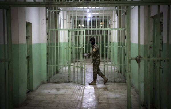 A member of the Syrian Democratic Forces stands guard in a prison where men suspected to be affiliated with ISIS are jailed in north-east Syria. [Fadel Senna/AFP]