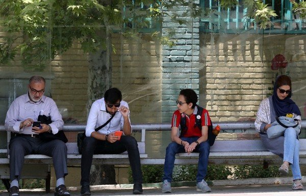 Des Iraniens se reposent sur un banc public le 8 juillet 2019 à Téhéran, la capitale. Le Centre de lutte contre le financement du terrorisme, à Riyad, a annoncé le 30 octobre de nouvelles sanctions contre 25 entités associées au CGRI iranien et au Hezbollah libanais. [STR/AFP]