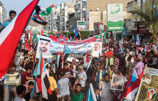 Des manifestants marchent en portant les drapeaux du sud Yémen et des Émirats arabes unis et une banderole arborant les visages du prince héritier d'Abou Dhabi, Mohammed ben Zayed al-Nahyan (à gauche), et du roi d'Arabie saoudite, Salmane ben Abdoulaziz (à droite), lors d'une manifestation baptisée « Marche de la gratitude pour l'Arabie saoudite et les Émirats arabes unis » à Aden, le 5 septembre. [Saleh al-Obeidi/AFP]