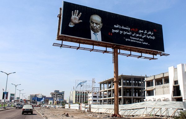 Une voiture passe devant un immense panneau publicitaire portant le portrait du président yéménite Abd Rabbo Mansour Hadi sur une route principale de la ville portuaire d'Aden. [Saleh al-Obeidi / AFP]