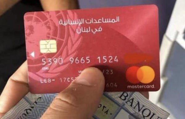 لاجئ سوري في لبنان يستخدم البطاقة الحمراء التي أصدرتها الأمم المتحدة لسحب المال المخصص للمساعدات الشتوية. [نهاد طوباليان/المشارق]