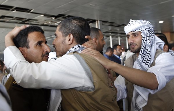 Un prisonnier Houthi étreint un homme le 28 novembre à son arrivée à l'aéroport à Sanaa, suite à sa libération, avec deux prisonniers, par une coalition menée par l'Arabie saoudite. [Mohammed Huwais/AFP]