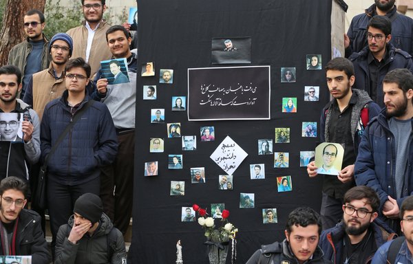 طلاب إيرانيون في جامعة طهران يحملون صورًا للضحايا أثناء حفل تأبين لركاب الطائرة الأوكرانية التي تم إسقاطها، وذلك يوم 14 كانون الثاني/يناير. [عطا كيناري/وكالة الصحافة الفرنسية]