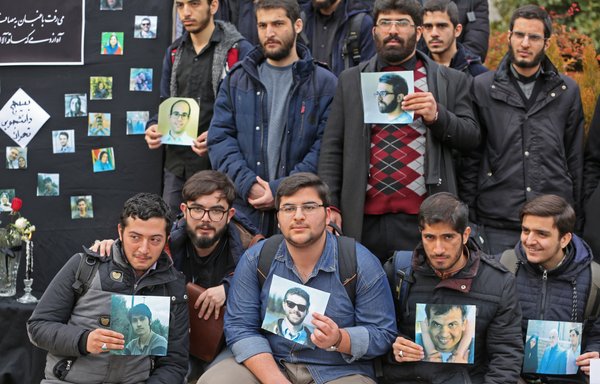 Des étudiants iraniens tiennent les photos des victimes lors d'un mémorial pour les passagers de l'avion ukrainien à l'université de Téhéran le 14 janvier. [Atta Kenare/AFP]