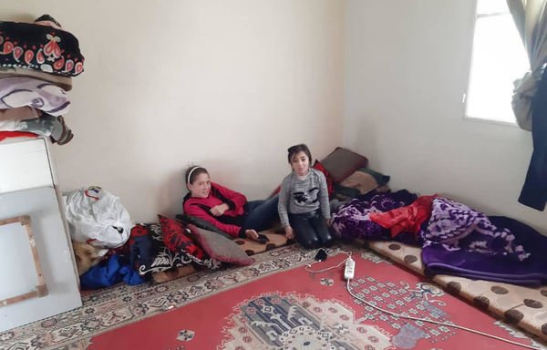 اللاجئة السورية رماس الخليل (إلى اليمين) تجلس على الأرض مع ابنة عمها علاء، في شقة أهلها الصغيرة في منطقة ديك المحدي اللبنانية.