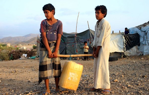 Boys carry together a jerry can filled with water from a cistern at a make-shift camp for displaced Yemenis in severe shortage of water, in the northern Hajjah province on March 24th. Hand-washing to combat the spread of COVID-19 is an unaffordable luxury for millions in war-ravaged Yemen where clean water is dangerously scarce. [Essa Ahmed/AFP]