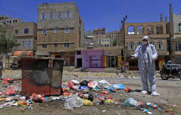 Un volontaire yéménite pulvérise un désinfectant sur des ordures dans l’un des quartiers pauvres de Sanaa, le 30 mars, dans un contexte d’inquiétudes concernant l’épidémie du nouveau coronavirus. [Mohamed Huwais/AFP]