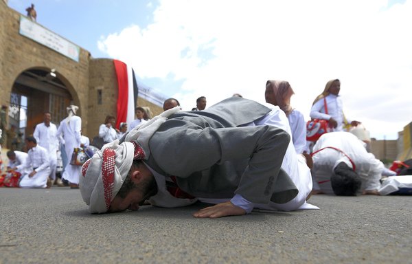 Des prisonniers yéménites, qui appartiendraient aux forces du pays, embrassent le sol après leur libération par les Houthis de la prison centrale de Sanaa avant d'être remis à leurs familles, le 30 septembre 2019. [Mohammed Huwais/AFP]
