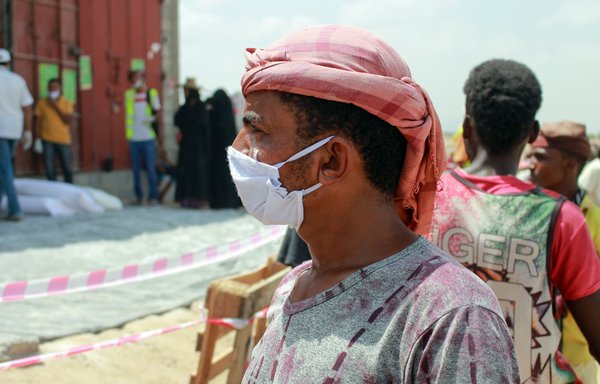 A displaced Yemeni man wearing a protective mask arrives to receive relief items distributed by employees of the World Food Programme amid the novel coronavirus pandemic, in Sanaa on April 18th. [Essa Ahmed/AFP]