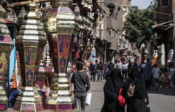 Des Égyptiens passent devant des lanternes traditionnelles appelées « fanous » en arabe et vendues pendant le mois sacré musulman du ramadan, le 19 avril, dans le quartier de Sayeda Zainab au Caire. [Mohamed al-Shahed/AFP]