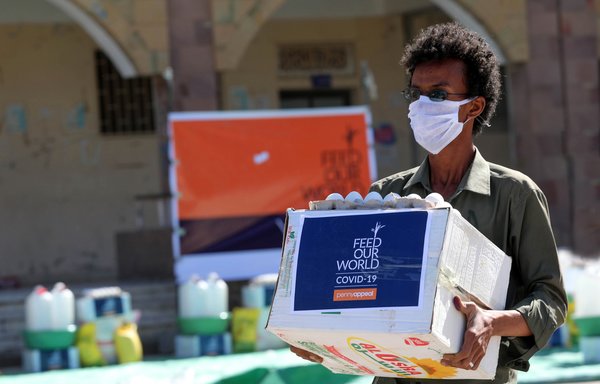 Un homme portant un masque de protection reçoit une aide humanitaire à Taez le 8 mai, pendant la pandémie du nouveau coronavirus. [Ahmad al-Basha/AFP]