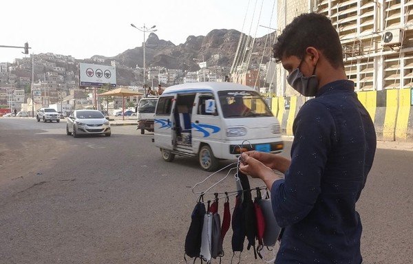 Un jeune portant un masque vend des masques dans une rue de la ville yéménite d’Aden le 17 mai, alors que l’on craint que le coronavirus ne se propage sans entrave dans cette ville. Les décès à Aden sont cinq ou sept fois plus nombreux que la normale, indiquent une ONG et des médecins. [Nabil Hasan/AFP]