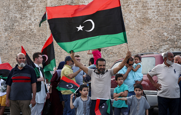Un homme brandit le drapeau national libyen le 4 juin, alors que les habitants font la fête dans la capitale Tripoli, après que le Gouvernement d’accord national (GAN), reconnu par les Nations unies, a déclaré avoir repris le contrôle total de la capitale et de ses banlieues à l’homme fort soutenu par la Russie. [Mahmoud TURQUIE/AFP]