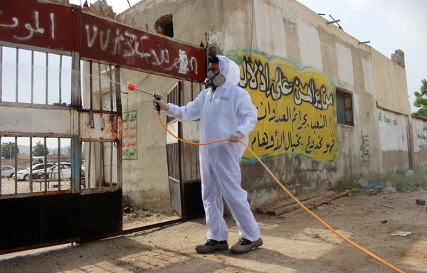 Un agent sanitaire yéménite, portant un équipement de protection, pulvérise du désinfectant dans un quartier de la province de Hajjah le 31 mai durant la crise du coronavirus. [Essa Ahmed/AFP]