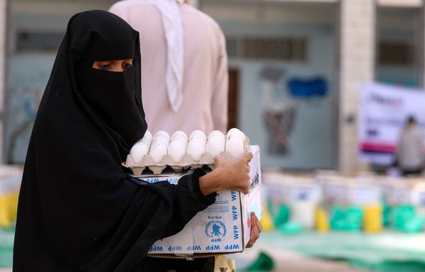 A woman wearing a protective mask receives humanitarian aid in Taez on May 8th, amid the coronavirus crisis. [Ahmad al-Basha/AFP]