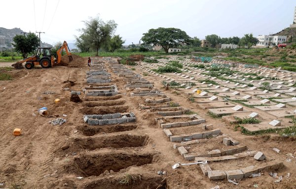 Des travailleurs yéménites utilisent une pelleteuse pour creuser des tombes sur un terrain réservé aux victimes de la COVID-19, le 14 juin dans un cimetière de Taez. [Ahmad al-Basha/AFP]