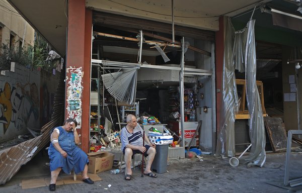 Une Libanaise blessée est assise devant sa boutique endommagée dans le quartier branché de Mar Mikhael à Beyrouth le 5 août, au lendemain de l’explosion massive survenue dans la capitale libanaise. [Patrick Baz/AFP]