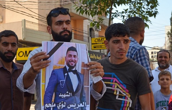 A man holds a poster bearing a picture of one of the soldiers killed during an overnight raid to arrest a suspected 'terrorist' in the Beddawi area near the northern port city of Tripoli on September 14th. [Fathi al-Masri/AFP]