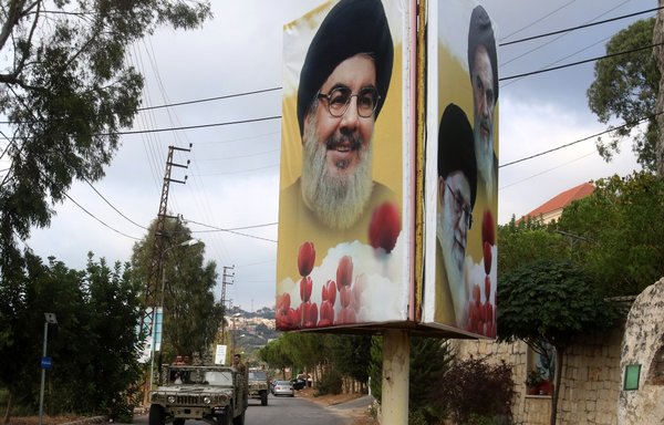 Un convoi de l'armée libanaise patrouille dans une rue d'Aïn Qana après qu'une explosion a touché un site du Hezbollah le 22 septembre. Une affiche montre le chef du Hezbollah Hassan Nasrallah, le Guide chef iranien Ali Khamenei et son défunt fondateur Rouhollah Khomeini. [Mahmoud Zayyat/AFP]