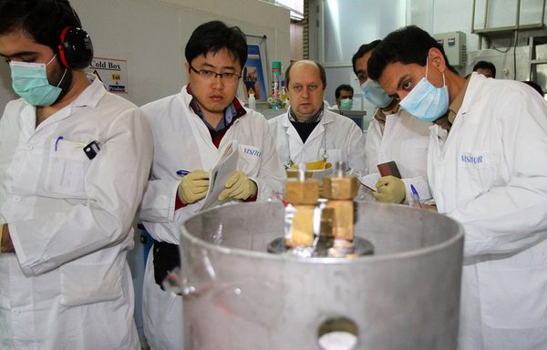 Des inspecteurs non identifiés de l'Agence internationale de l'énergie atomique et des techniciens iraniens débranchent les raccordements entre les cascades jumelles pour la production de 20% de l'uranium dans une centrale nucléaire à Natanz sur cette photo d'archive du 20 janvier 2014. [Kazem Ghane/IRNA/AFP]