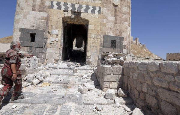 A member of the Syrian regime forces stands near the partially destroyed entrance of Aleppo's citadel on September 4, 2012, a day after regime troops backed by artillery and warplanes battled opposition fighters on multiple fronts. [Joseph Eid/AFP]