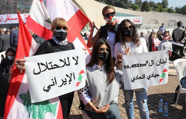 Lebanese protesters on February 27 carry banners protesting the 'Iranian occupation' and calling for Lebanese sovereignty at the Maronite Patriarchate in Bkerki, northeast of Beirut. [Anwar Amro/AFP]